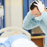 doctors clenching head, patient in bed | medical malpractice attorney